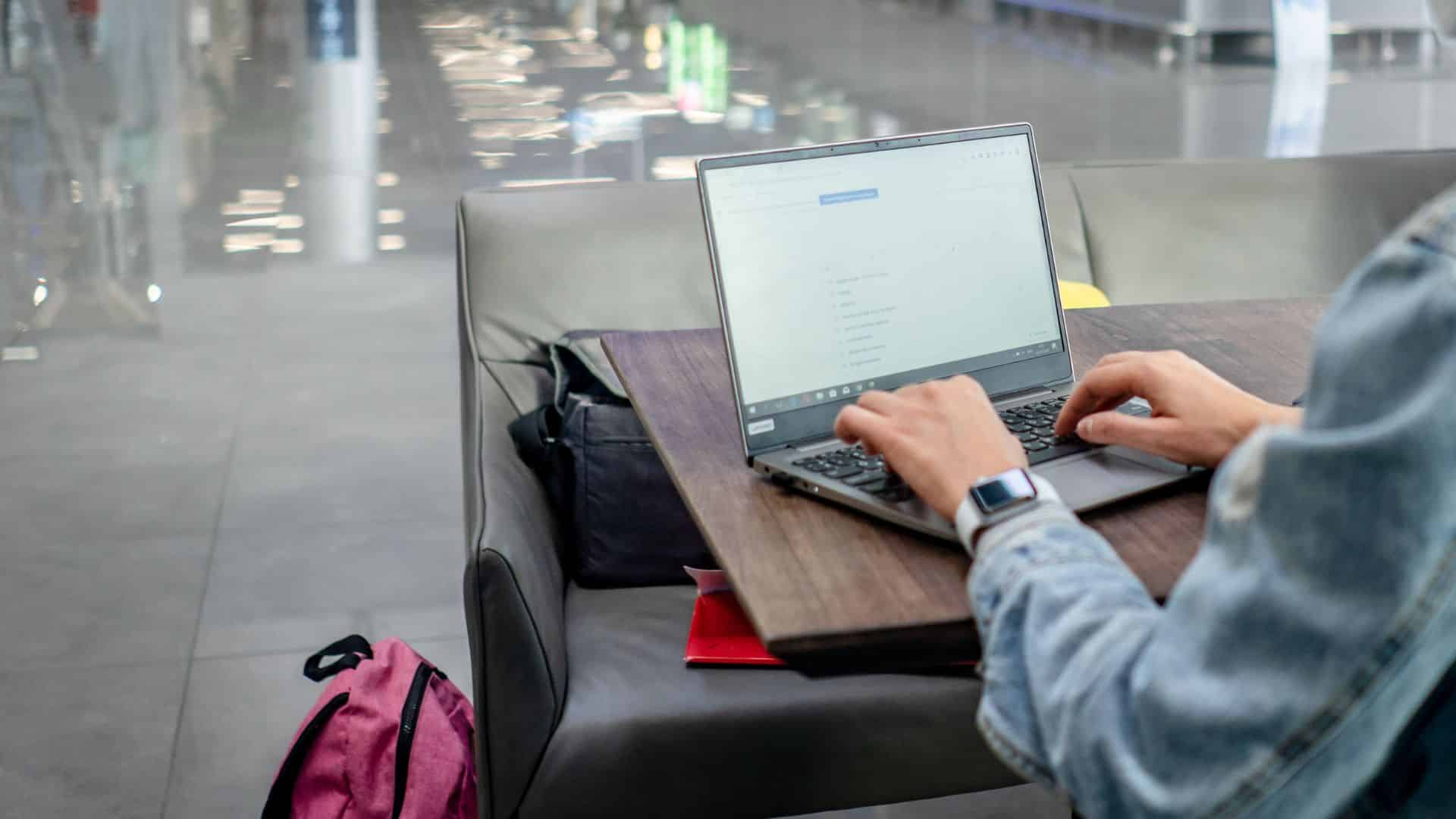 Henkilö työskentelee kannettavalla tietokoneella julkisessa tilassa.